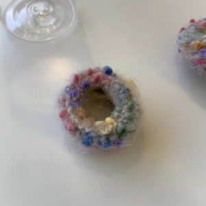 Makroansicht des Plüsch-Strick-Haargummis mit bunten Wollkugeln und grauer Basis