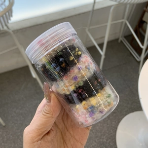 Detail von bunten Plüschball-Haargummis-Set in einem transparenten Plastikglas verpackt