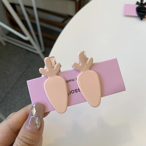 Detail view of two cute pink resin carrot-shaped hair clips on a purple display card