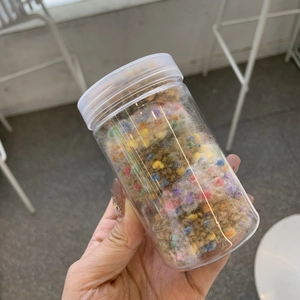 Dose mit bunten Mini-Bastelbommeln für DIY-Handwerksprojekte und Haarschmuck