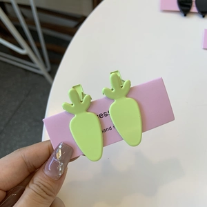 Close-up of two matte green carrot-shaped hair clips on a pink presentation card