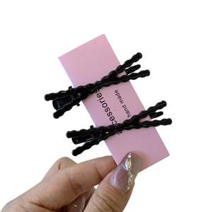 Set di due forcine per capelli nere ondulate per donna su un elegante supporto rosa