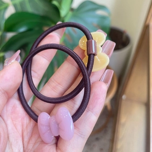 Detail van twee elastische haarelastiekjes met halftransparante jelly-strikjes in roze en geel