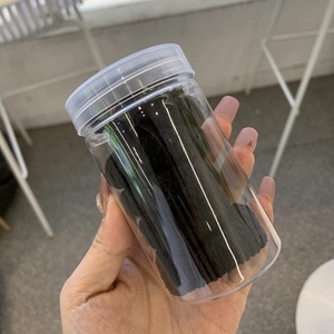 Détail de chouchous élastiques noirs épais dans un récipient de rangement transparent