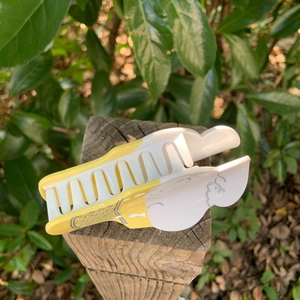Pinza per capelli a forma di gelato color crema posata su legno rustico nella natura