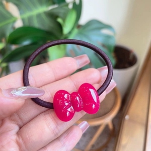 Detail van elastisch haarelastiekje met een glanzende roze strik van hars op de hand