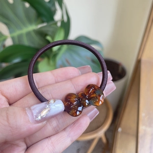 Detail van een bruine elastische haarelastiek met een doorschijnende amberkleurige strik