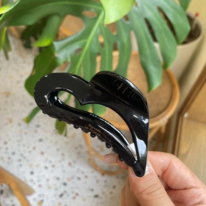 Detail of a black heart-shaped acetate hair claw clip with golden Barrette La France text