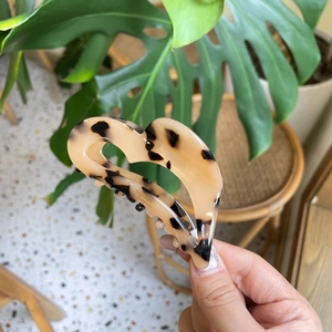 Macro detail of heart-shaped acetate claw clip with classic tortoiseshell leopard print