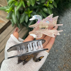 Detailed close-up of swan cellulose acetate hair claws with elegant golden metal spring