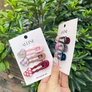 Close-up of heart-shaped jelly hair clips with wavy design held in hand outdoors