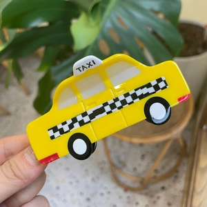 Detail shot of a yellow taxi-shaped acetate hair claw clip with black and white grid patterns