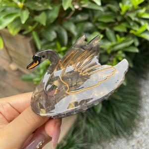 Elegant swan hair claw clip with black and gold marble pattern made of cellulose acetate