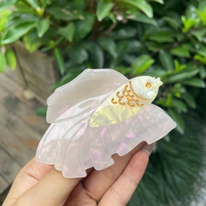 Elegant fish-shaped hair claw clip in pearl white acetate with golden fish scales