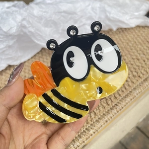Cute bee-shaped acetate hair claw clip with yellow marble texture and sparkling rhinestones
