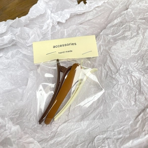 Two-piece set of minimalist matte duckbill hair clips in tan and cream colors on card