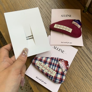 Detailed view of the woven plaid rabbit hairclip with heart accents and silver metal base