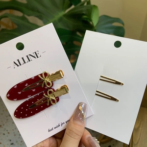 Détails de barrettes rouges à pois avec nœuds dorés sur carte de présentation