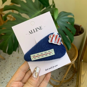 Navy blue knitted rabbit ear hairpin with striped pattern and crystal on a display card