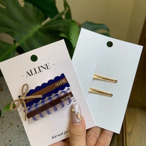 Detail of blue and checkered bow hair clips with Alline text on a display card