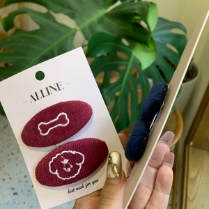 Detailed embroidery of dog and bone patterns on corduroy hair clips in wine red and navy