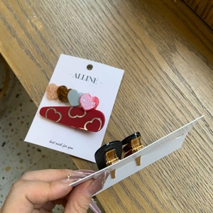 Détail d'un ensemble de barrettes à cheveux avec base cœur rouge et breloques colorées
