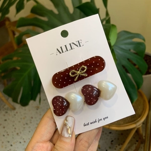 Polka dot hair clip set with hearts and golden bow on white brand card background