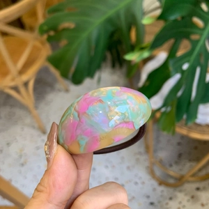 Handheld photo of a marbled acetate hair tie with colorful resin oval decor in soft sunlight