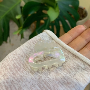 Elegant heart-shaped acetate hair claw clip with pearlescent white finish and gold logo