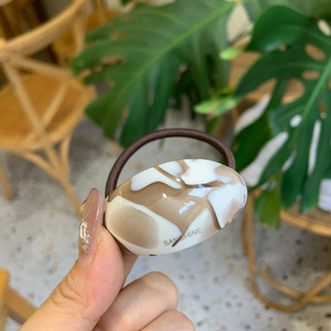 Detailed close-up of marble pattern resin plate on elastic hair band with logo
