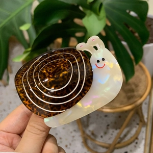 Detail of snail-shaped acetate hair claw featuring leopard print and pearly finish