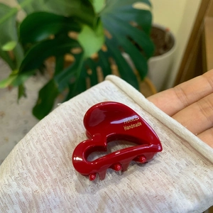 Detailed macro view of heart-shaped red acetate hair claw clip with golden France Handmade text