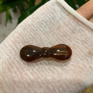 Detail of amber brown acetate bow hair clip with gold France Handmade lettering