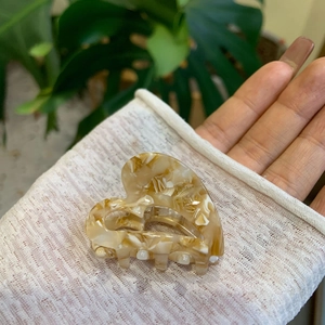 Macro detail of heart-shaped marble acetate hair claw with golden handmade text