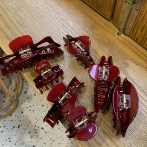 Set dettagliato di sette mollette per capelli bordeaux in varie dimensioni su legno