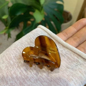 Detail of a handmade heart-shaped acetate hair claw clip with amber tortoise shell pattern