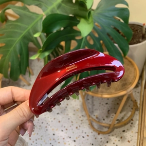 Dettaglio della pinza per capelli in acetato bordeaux con logo dorato France Handmade