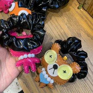 Détails de peluches de monstre et d'ours sur des chouchous en similicuir noir brillant