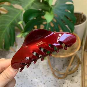 Dettaglio del fermaglio per capelli bordeaux in acetato con scritta dorata lucida
