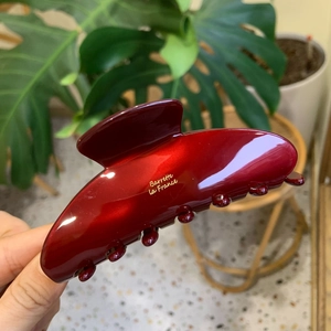 Dettaglio macro della pinza per capelli in acetato bordeaux con scritta dorata Barrette La France