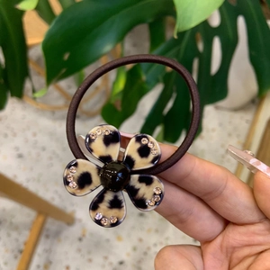 Detailed macro view of a leopard print flower hair tie with pink rhinestones and black core