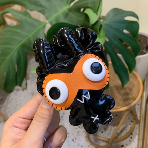 Gros plan d'un chouchou monstre noir en cuir PU brillant avec un masque orange vif