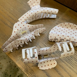 Detail view of 4-piece acrylic hair claw set with red polka dots on ivory background