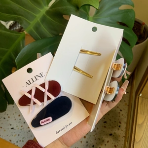 Detailed close-up of ribbon bow hair clips and logo hairpins on brand cards