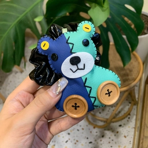 Macro d'un chouchou ours en similicuir avec boutons en bois et coutures bleues