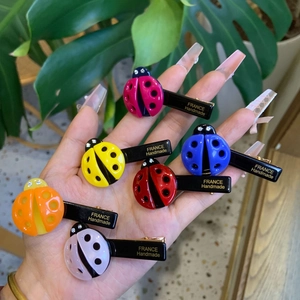 Set of seven colorful ladybug hair clips with crystal accents and gold logo details