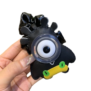 Chouchou monstre en similicuir noir avec un grand œil unique et un motif de bouche jaune