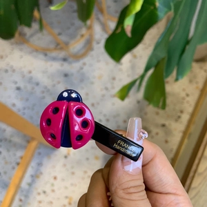 Cute ladybug hair clip with pink shell and rhinestones shown in a bright outdoor setting