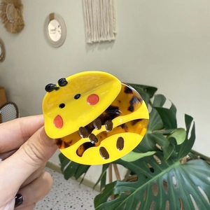 Detailed close-up of a cute cartoon bee hair claw clip made of yellow and tortoise acetate
