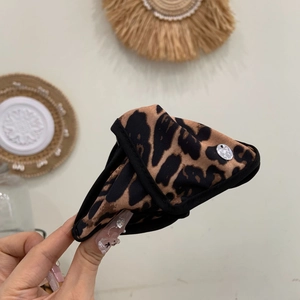 Detail shot of leopard print fabric hair claw with premium silver metallic branding tag